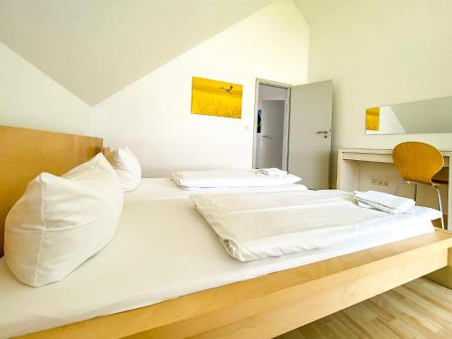 1 cama con almohadas blancas y espejo en una habitación en Ferienhaus Wiesengeflüster S1 - mit Sauna, Kamin und Workation an der Müritz en Marienfelde