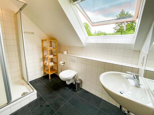 uma casa de banho com um lavatório, um WC e uma janela. em Ferienhaus Wiesengeflüster S1 - mit Sauna, Kamin und Workation an der Müritz em Marienfelde