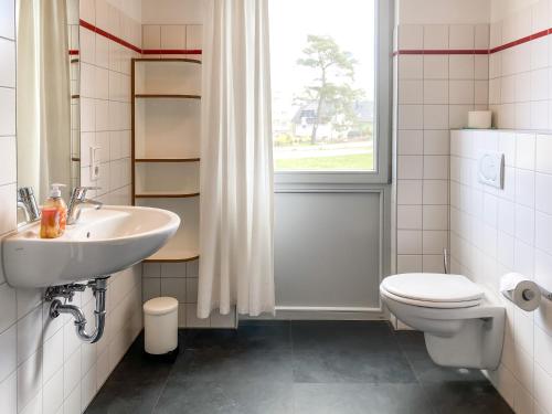 a bathroom with a sink and a toilet and a window at Gruppenunterkunft Wiesengeflüster S2 mit Wiesenblick, Sauna und Kamin in Röbel