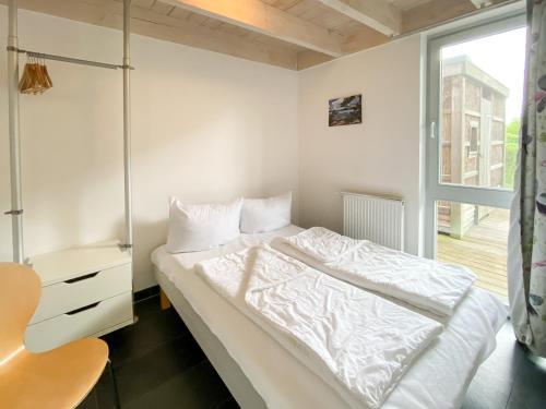 a bedroom with a white bed and a window at Ferienhaus Wiesengeflüster E3 - familienfreundlich nur 3 Minuten zum Strand in Röbel