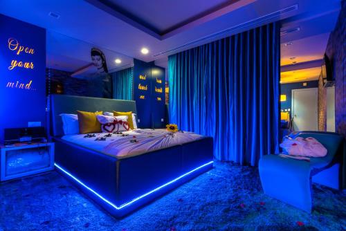 a blue bedroom with a bed and a sign on the wall at Motel Emoções in Nogueira da Regedoura