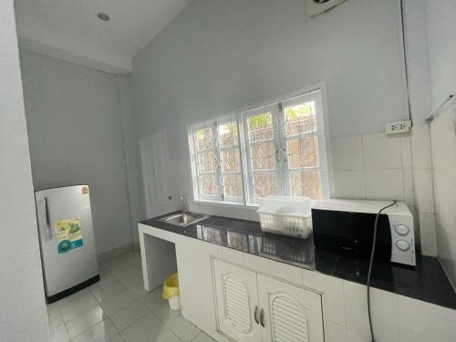 eine Küche mit einer Spüle, einer Mikrowelle und einem Kühlschrank in der Unterkunft VS appartment in Vientiane