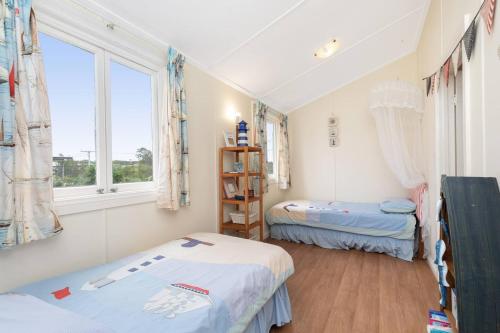 twee bedden in een kamer met twee ramen bij Coastal Queenslander with Fraser Island Views in Boonooroo