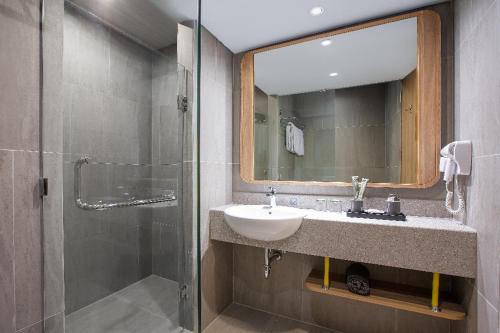 a bathroom with a sink and a mirror and a shower at Harper Banjarmasin in Banjarmasin