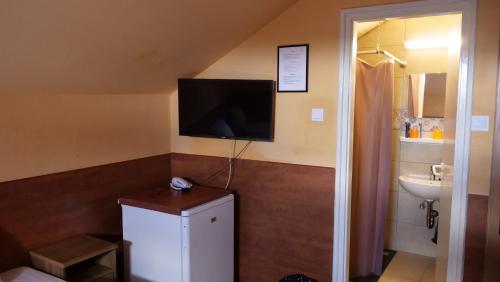 a bathroom with a tv on the wall and a sink at Attila Hotel Budapest in Budapest