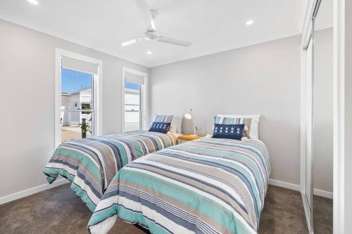 two beds in a room with a window at 'Esplanade Escape' A Fresh Coastal Family Hideaway in Urangan