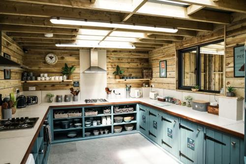 a kitchen with blue cabinets and wooden walls at Glamping at Macdonald's Farm in Saint Ervan