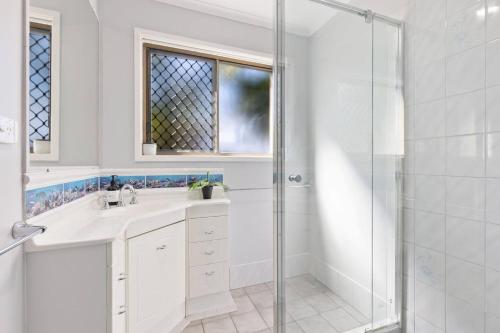 baño blanco con ducha y lavamanos en Torquay Beach Splendour - An Expansive Family Stay en Torquay