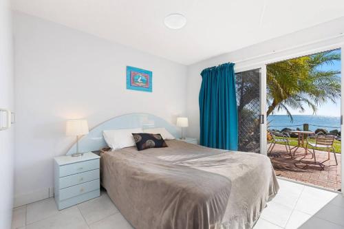 a bedroom with a bed and a view of the ocean at Sandy Straits Poolside Escape with Beach Access in Hervey Bay