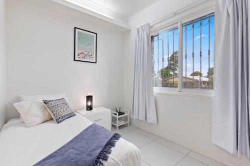 um quarto branco com uma cama e uma janela em Little Miss Sunshine - An Oceanside Family Delight em Hervey Bay