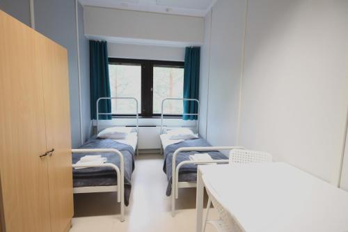 a hospital room with three beds and a table at Forenom Hostel Espoo Kilo in Espoo