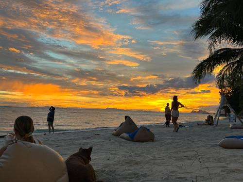 a group of people on the beach at sunset at Sarana Bungalows in Baan Tai