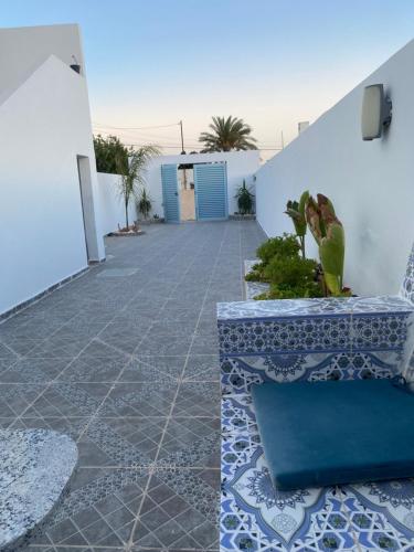 a patio with blue and white tiles and a bench at Studio Rouge Cosy à Dar Lili Djerba in Mezraya
