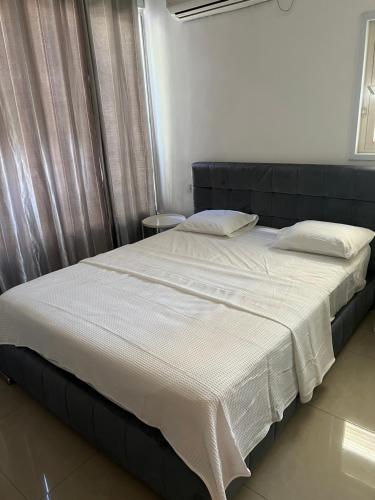- un lit avec des draps et des oreillers blancs dans une chambre dans l'établissement Center boutique Apartment, à Netanya