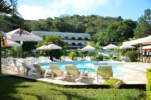 einen Pool mit Stühlen und Sonnenschirmen neben einem Gebäude in der Unterkunft Hotel Green Hill in Juiz de Fora