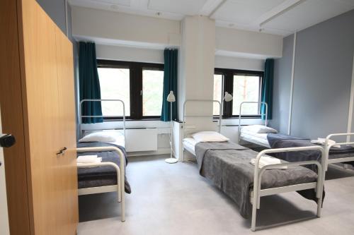 a room with three beds and two windows at Forenom Hostel Espoo Kilo in Espoo
