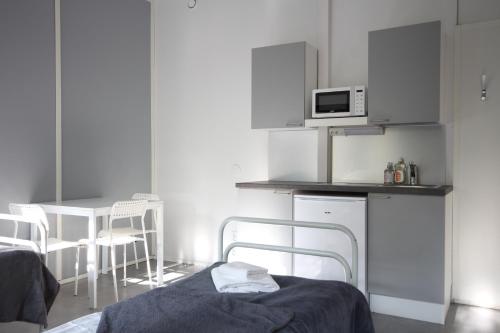 a room with a bed and a kitchen with a microwave at Forenom Hostel Espoo Kilo in Espoo