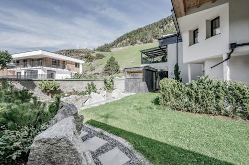 un patio trasero de una casa con una pared de piedra en Corso Living, en Sölden