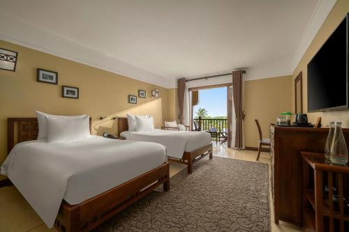 a hotel room with two beds and a television at La Siesta Hoi An Resort & Spa in Hoi An