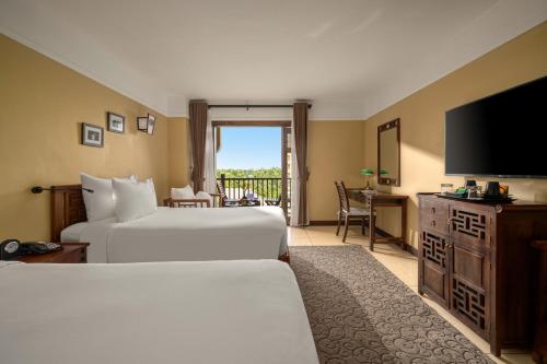 a hotel room with two beds and a flat screen tv at La Siesta Hoi An Resort & Spa in Hoi An