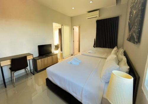 a bedroom with a bed and a desk and a television at Zada Residence in Nakhon Ratchasima