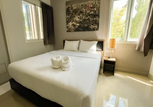 a bedroom with a large white bed with two shoes on it at Zada Residence in Nakhon Ratchasima