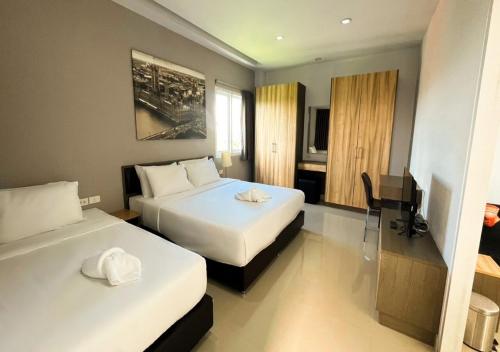 a hotel room with two beds and a desk at Zada Residence in Nakhon Ratchasima