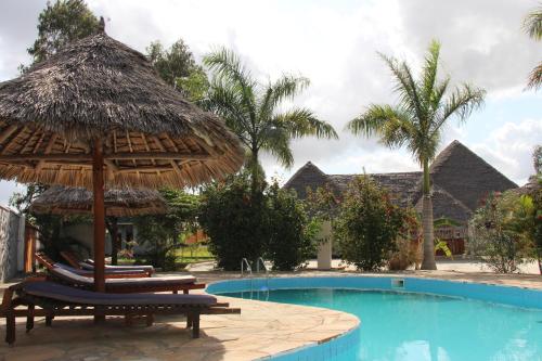 a resort with a swimming pool with chairs and a straw umbrella at Mapeni Lodge in Kidenge