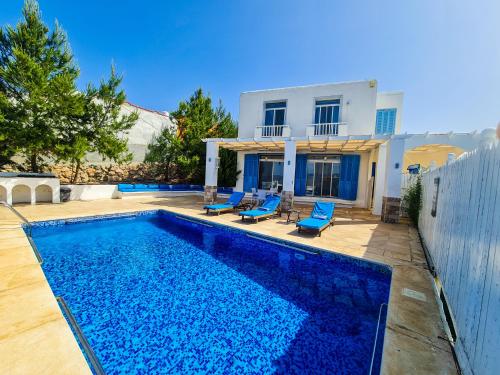 a swimming pool with blue chairs and a house at VILLA NAYA Branch 3 - SANTORINI, Jerash in Rujm al Miḑmār