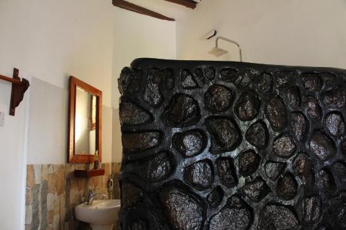 a bathroom with a stone wall next to a sink at Mapeni Lodge in Kidenge
