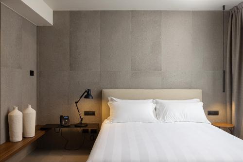 una camera da letto con un grande letto con lenzuola bianche di B21 Lifestyle Hotel a Bari