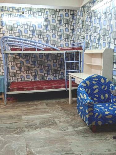 Zimmer mit einem Bett, einem Stuhl und einem Tisch in der Unterkunft Venus Homestay in Kalkutta