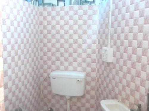 a bathroom with a toilet and a pink checkered wall at Venus Homestay in Kolkata