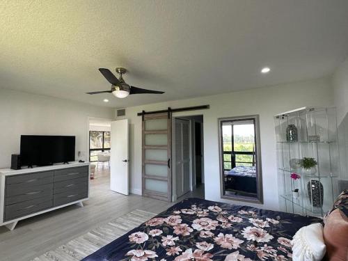 a living room with a ceiling fan and a tv at The Delightful Golf Villa in Palm Beach Gardens