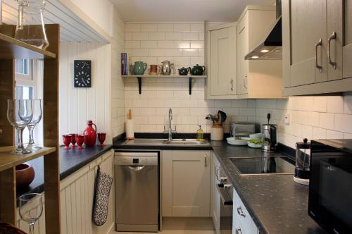 a kitchen with white cabinets and a sink at Smithy Cottage in Strathdon