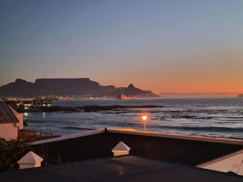 a view of the ocean at sunset from a balcony at Cape Town, Sea Point, Beautiful 2 Bedroom Apartment @Tucked Away in Cape Town