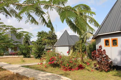 a house with a garden and a palm tree at Mapeni Lodge in Kidenge