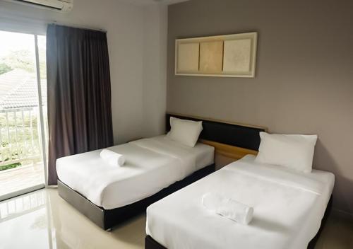 a hotel room with two beds and a window at Zada Residence in Nakhon Ratchasima