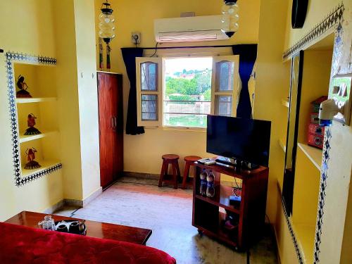 a living room with a red couch and a television at Oolala - Your lake house in the center of Udaipur in Udaipur