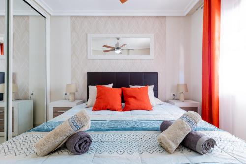 Un dormitorio con una cama grande con almohadas rojas. en Modern apartment in Golf del Sur, AC237, tempered pool and ocean view, en San Miguel de Abona