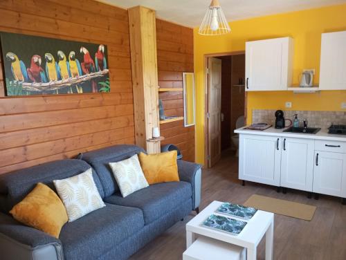 a living room with a couch and a kitchen at Gîte du Chalet - Le studio en pleine nature 