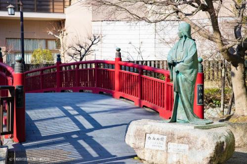 a statue of a woman on a red bridge at KAMENOI HOTEL Arima in Kobe