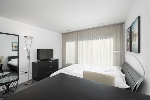 Studio PAOLA Interlaken في إنترلاكن: غرفة نوم بيضاء فيها سرير وتلفزيون