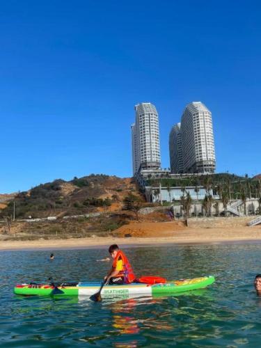 a man paddling a kayak in the water near a beach at Apec Mandala Cham Bay Condotel Mui Ne in Mui Ne