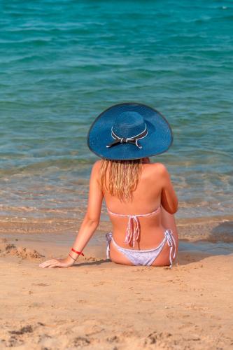 a woman in a blue hat sitting on the beach at Siva Golden Bay Makadi in Hurghada