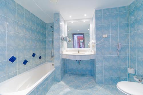 a blue tiled bathroom with a tub and a sink at Siva Golden Bay Makadi in Hurghada