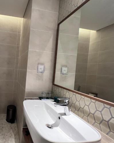 a bathroom with a sink and a large mirror at Apec Mandala Cham Bay Condotel Mui Ne in Mui Ne