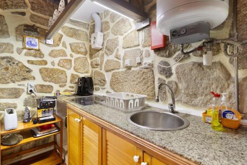 een keuken met een wastafel en een stenen muur bij Casa Azenha Branca in Esposende