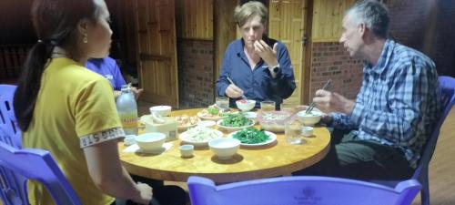 Eine Gruppe von Menschen, die an einem Tisch sitzen und Essen essen. in der Unterkunft Long Linh Homestay in Sa Pả
