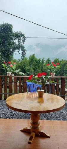 einen Holztisch mit Blumen auf dem Balkon in der Unterkunft Long Linh Homestay in Sa Pả